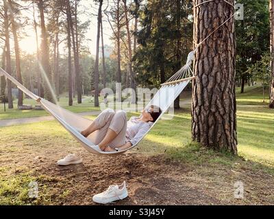 Donna in età media che si rilassa su amaca nel parco in estate Foto Stock