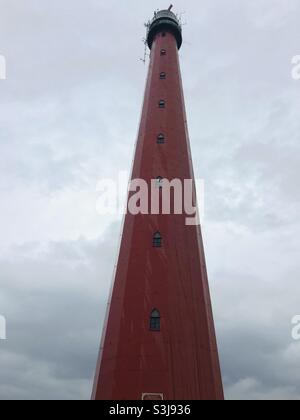 Faro rosso a Den Helder, Olanda, di fronte a un cielo nuvoloso in una giornata piovosa Foto Stock