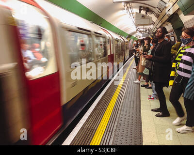 I passeggeri aspettano sul binario alla stazione della metropolitana di Paddington, quando un treno arriva al binario. Foto Stock