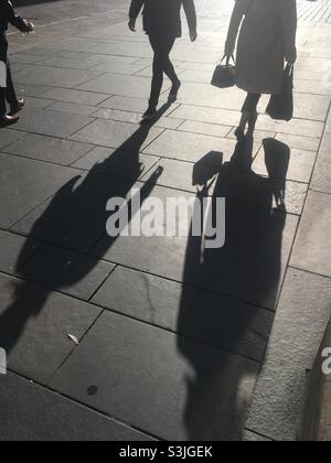 Silhouette sul marciapiede delle persone che fanno shopping o che si fanno pendolari in città Foto Stock