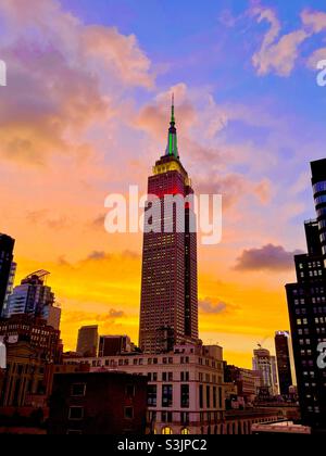 Un tramonto luminoso e colorato sulla città di New York con una silhouette dell'Empire state Building e di altri grattacieli Foto Stock
