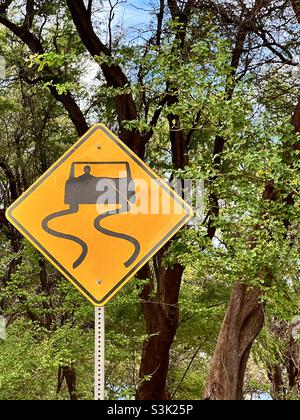 Segnale stradale di avvertimento per curve pericolose che precedono su una strada di campagna remota. Foto Stock