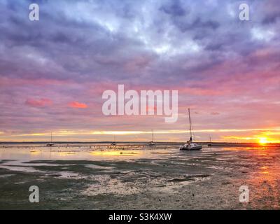 Tramonto a bassa marea a Leigh-on-Sea con piccole barche seduti sul fango dell'estuario del Tamigi Foto Stock