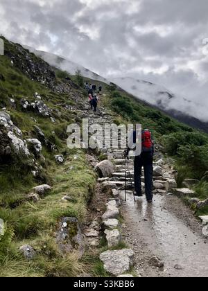 Persone che iniziano a camminare lungo il ripido sentiero del ben Nevis in Scozia Foto Stock