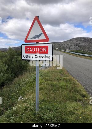 Un cartello stradale Otters Crossing avverte la gente di rallentare su una strada nelle Ebridi esterne in Scozia Foto Stock