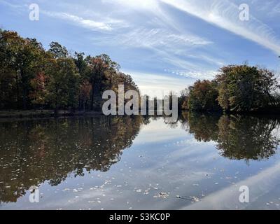 Gli alberi nei loro colori autunnali si riflettono in un laghetto calmo e tranquillo in uno splendido pomeriggio di novembre in New Jersey Foto Stock