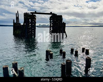 A Port Townsend, un traghetto dello stato di Washington passa davanti ai vecchi moli vicino al centro sulla via di uscita dalla città in un pomeriggio di novembre. Foto Stock