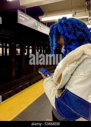 Una donna dai capelli blu aspetta la metropolitana a New York City Foto Stock