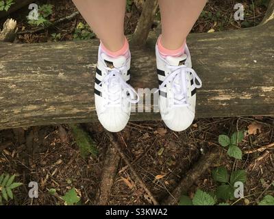 Ragazza con sneakers Adidas superstar bianche in legno Foto Stock