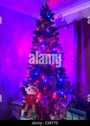 Un albero di Natale illuminato con luci rosse e blu. Foto Stock