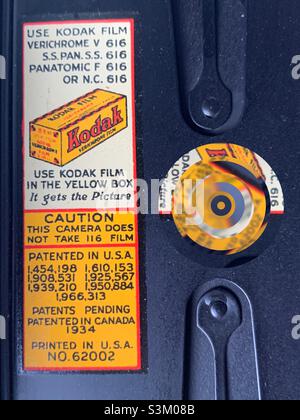 Etichetta Kodak (circa 1934) all'interno di questa fotocamera antica. Il cerchio prismatico e astratto sulla destra è stato aggiunto digitalmente e potrebbe rappresentare l’obiettivo, l’apertura, l’otturatore o l’anello di messa a fuoco di una telecamera. Foto Stock