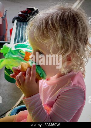 Bambina di due anni che mangia cupcake con glassa verde. Foto Stock