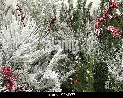 Le composizioni floreali artificiali di Natale sono vendute presso un Walmart locale nello Utah, Stati Uniti. Molto stagionale con aghi di pino verde, bacche rosse e floccaggio per dare un aspetto glassato. Foto Stock