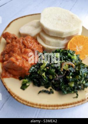 Il filato affettato bollito con manzo stufato di pomodoro e verdure verdi saltate, cibo Ghanaiano o nigeriano Foto Stock