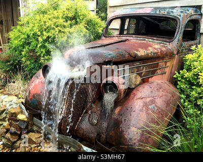 Antico camion arrugginito convertito in una fontana d'acqua giardino. Foto Stock