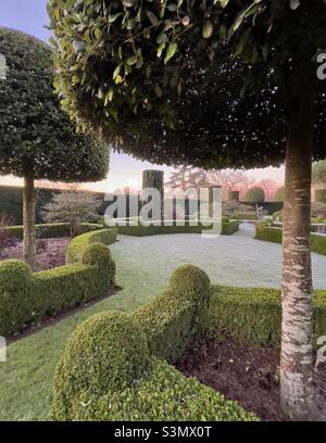 Il parterre di una casa di campagna giardino con topiario presto in una gelida mattina d'inverno Foto Stock