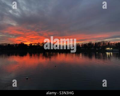 Bellissimo tramonto invernale rosso al parco di Idroscalo con il suo riflesso nel lago di Milano Foto Stock