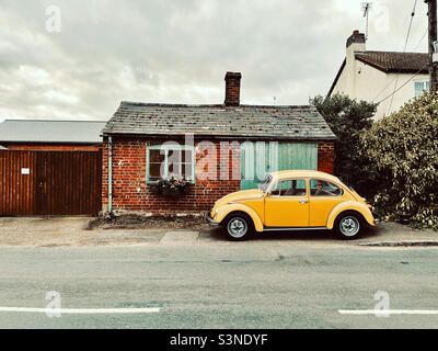 Classico giallo VW Beatle di fronte al vecchio garage. Foto Stock