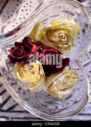 Una tavola di rose secche e un piatto cristallino a forma di cuore Foto Stock