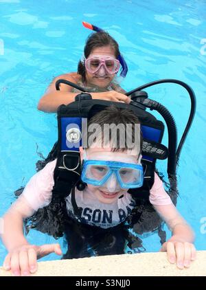 Giovane ragazzo imparando a fare immersioni, il suo istruttore controlla le sue attrezzature Foto Stock