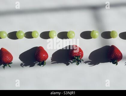 Filari di uve verdi e fragole Foto Stock