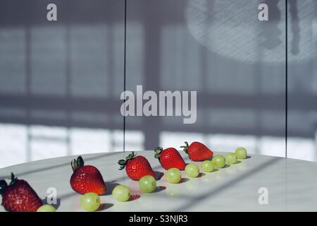 Filari di uve verdi e fragole Foto Stock
