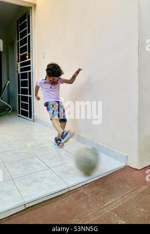 il ragazzo di 5 anni calcia una palla di calcio in aria. L'Avana, Cuba, Caraibi Foto Stock