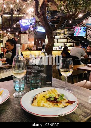 Due bicchieri di vino e una fetta di pizza al Gordon Ramsay’s Street Pizza di Londra Foto Stock