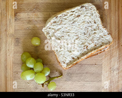 Panino e uva su tavola di legno Foto Stock
