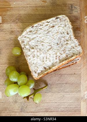 Panino e uva su tavola di legno Foto Stock