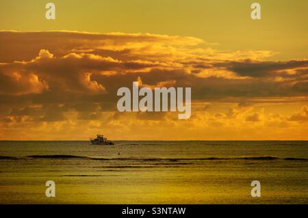 Sfondo bellissimo tramonto con una barca sul mare al Ala Moana Beach Park a Honolulu città Oahu isola Hawaii, una destinazione di viaggio per i turisti Foto Stock