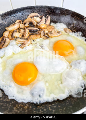 Uova e funghi in una padella Foto Stock