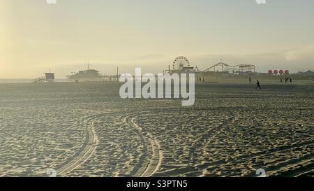 Ammira la spiaggia di Santa Monica con il molo all'orizzonte e la catena montuosa a malapena visibile nelle lontane e nel tardo pomeriggio Foto Stock