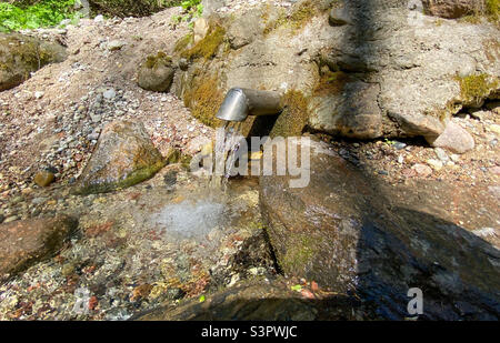 Una molla fresca e fredda fluisce dal terreno. Acqua fresca e deliziosa. Fonte naturale di acqua sotterranea Foto Stock