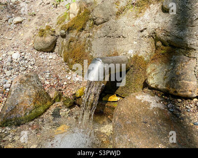 Una molla fresca e fredda fluisce dal terreno. Acqua fresca e deliziosa. Fonte naturale di acqua sotterranea Foto Stock