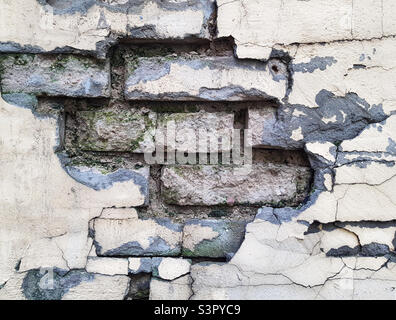 Sfondo di un muro di mattone sbriciolato primo piano. La consistenza di una parete sbriciolante Foto Stock