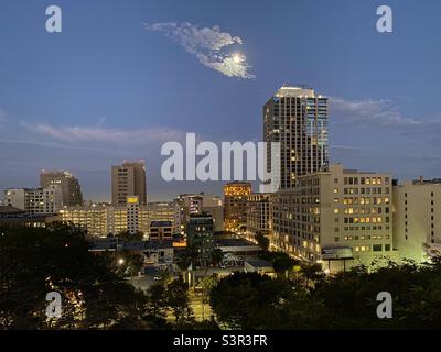 LOS ANGELES, CA, GIUGNO 2021: Vista notturna dello skyline del centro città con la luna sopra i nuovi sviluppi residenziali, negozi e uffici Foto Stock
