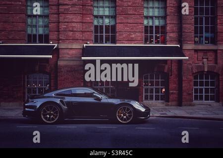 Supercar sport auto Porsche coupé parcheggiato all'esterno di un lussuoso magazzino appartamento Foto Stock