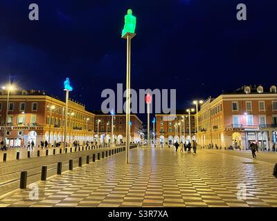 Foto notturna di Place Massena a Nizza sulla Côte Azzurra francese con le sue statue illuminate e il pavimento geometrico Foto Stock