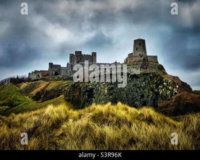 ‘Dune-view’ il magnifico Castello di Bambburgh sovrasta la costa del Northumberland, vista dalle dune di sabbia che si avvicinano alla spiaggia sottostante Foto Stock