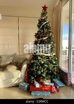 Albero di Natale artificiale con i regali avvolti sotto Foto Stock