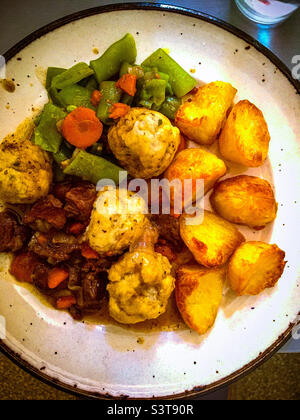 Stufato di manzo e gnocchi con patate arrostite e verdure Foto Stock