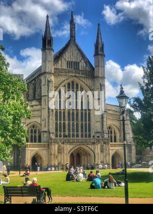 Winchester Cathedral e le persone che godono del sole primaverile nei giardini della cattedrale Foto Stock