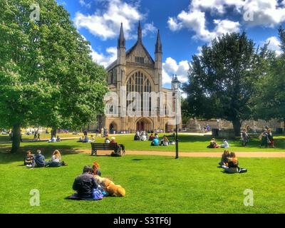 Persone che godono del sole primaverile nella Winchester Cathedral Grounds, Regno Unito Foto Stock