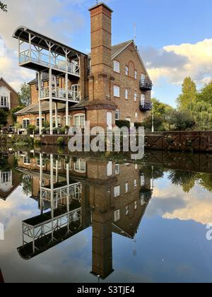 Riflesso di appartamenti Mill convertiti sopra il Tamigi si blocca sul fiume Wey a Weybridge, Inghilterra in una serata estiva. Foto Stock