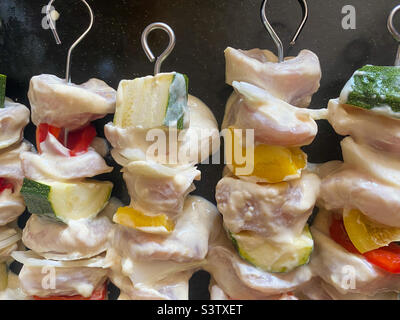 Pollo crudo marinato e verdure su spiedini di metallo che compongono kebab fatti in casa. Foto Stock