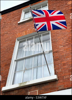 La bandiera del Regno Unito (Union Jack) sbatte fuori dalla finestra di una casa in Gran Bretagna. Foto ©️ COLIN HOSKINS. Foto Stock
