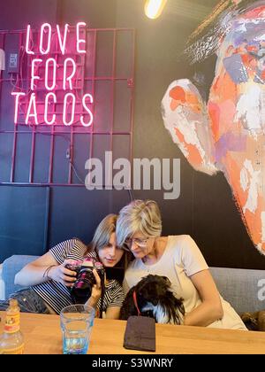 Madre e figlia che tiene il cane e chiacchierare nel ristorante tacos Foto Stock