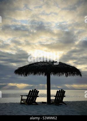 Due sedie a sdraio vuote sotto un palapa in una mattina presto alba nelle Fiji. Resort sull'Isola di Tavarua, Fiji. Foto Stock