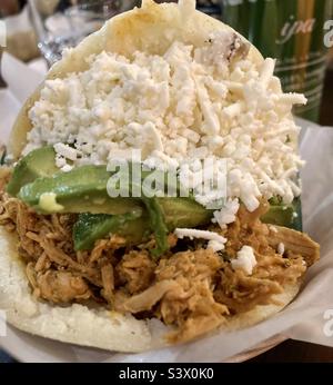 Arepa venezuelana farcita con pollo tirato, avocado e formaggio feta. Foto Stock